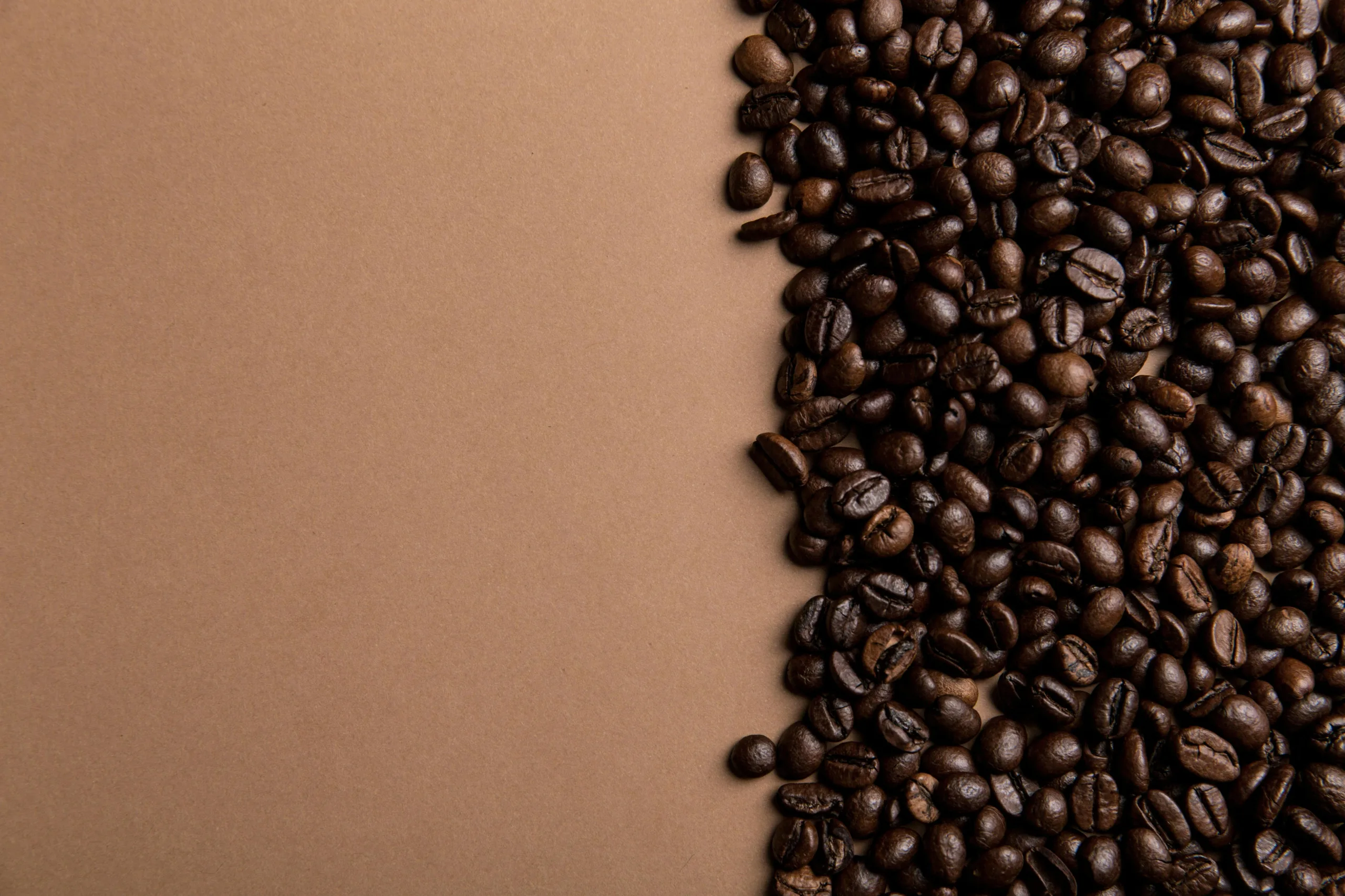 Espresso beans spilling from a bag beside a fresh espresso shot on a rustic wooden table